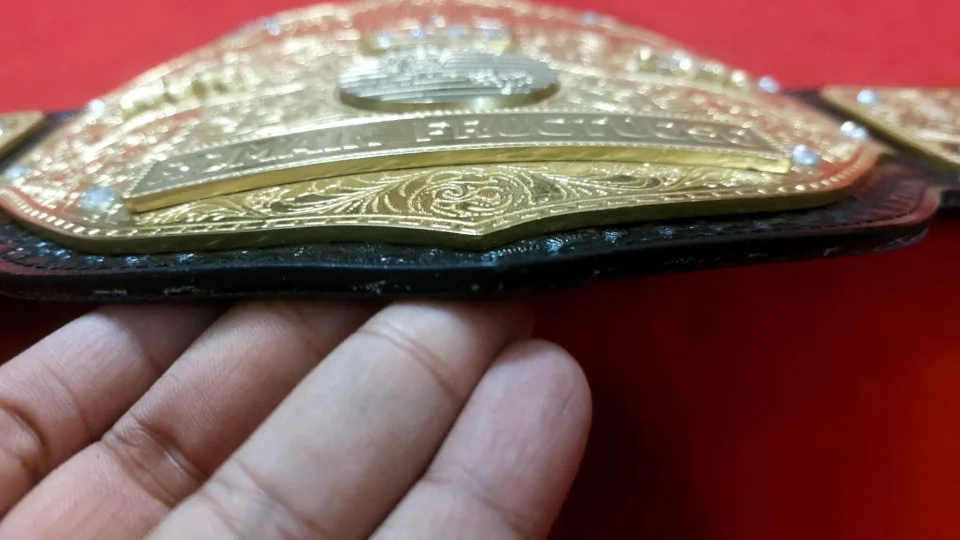 Craftsman hand finishing a cast championship belt plate at the Ibrahim Sports workshop in Sialkot