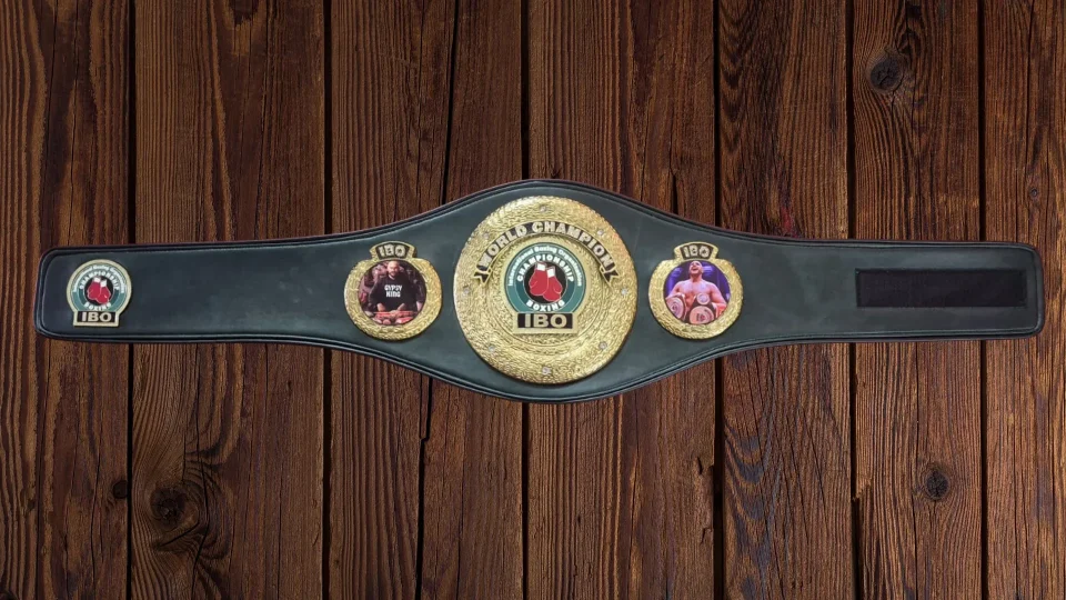 Full size replica championship belt with custom side plates showing both heavyweight fighters, on a workbench