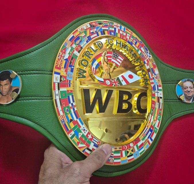 Green and gold WBC-style championship belt, close-up on the engraved center plate
