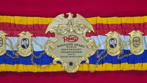 Finished boxing championship belt laid flat on a workbench with its full 48 inch strap visible