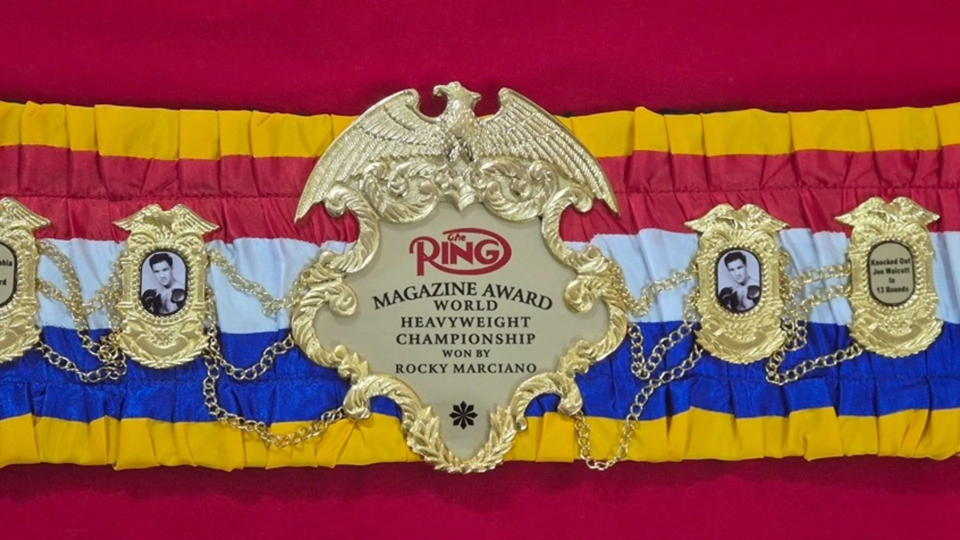 Finished boxing championship belt laid flat on a workbench with its full 48 inch strap visible