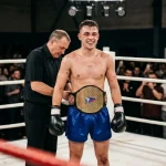 Amateur kickboxer having a championship belt fastened around the waist in the ring after a title fight