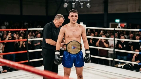 Amateur kickboxer having a championship belt fastened around the waist in the ring after a title fight