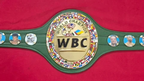 Green WBC belt replica with hand painted world flags and gold plated side plates on a workbench in Sialkot