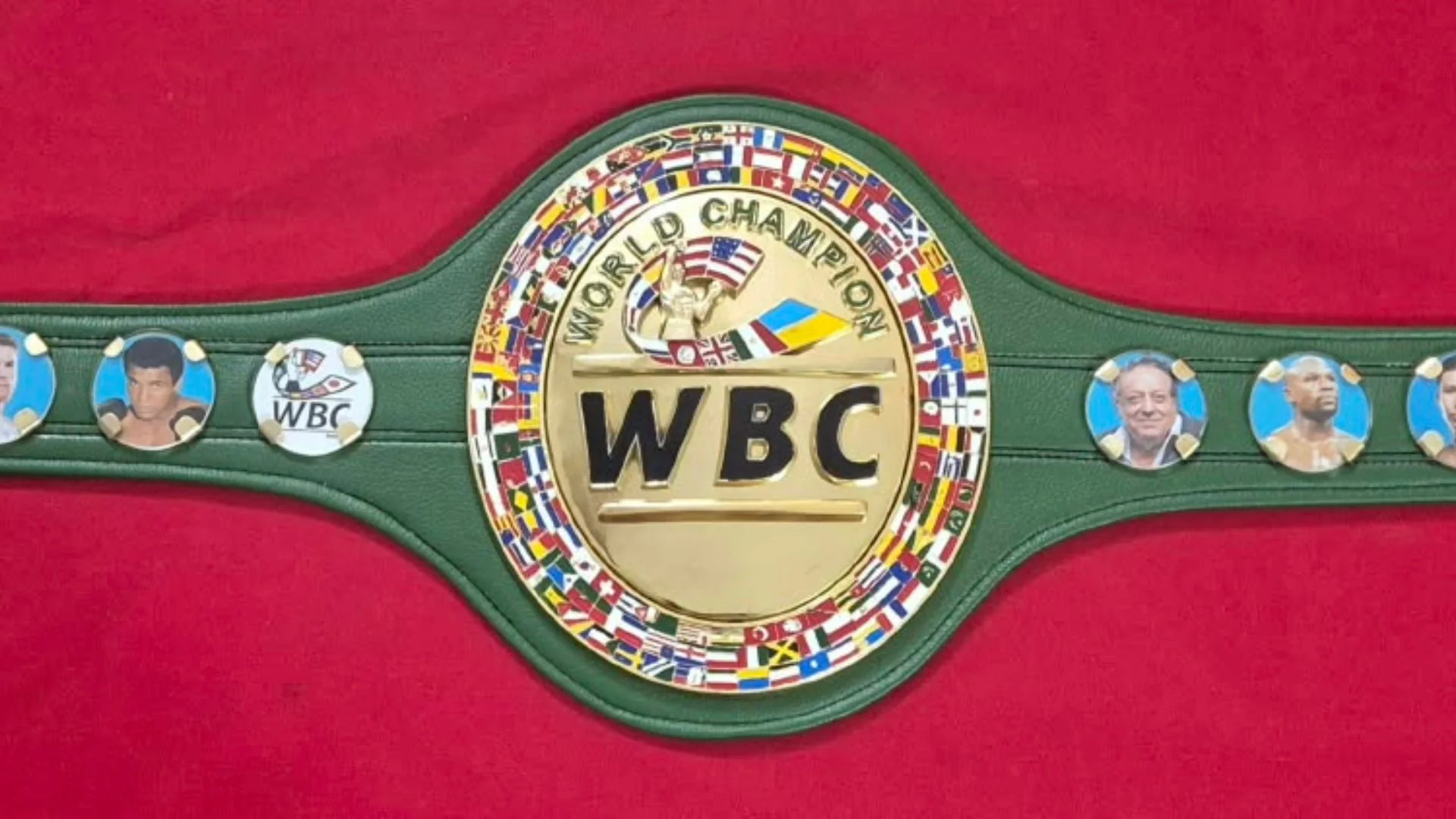 Green WBC belt replica with hand painted world flags and gold plated side plates on a workbench in Sialkot